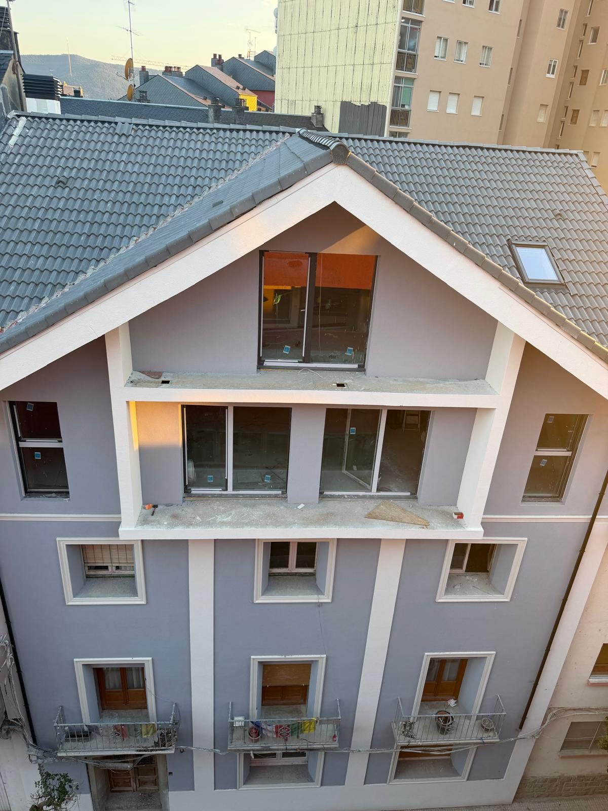 Fachada terminada del edificio rehabilitado en Jaca, en tonos gris azulado y blanco